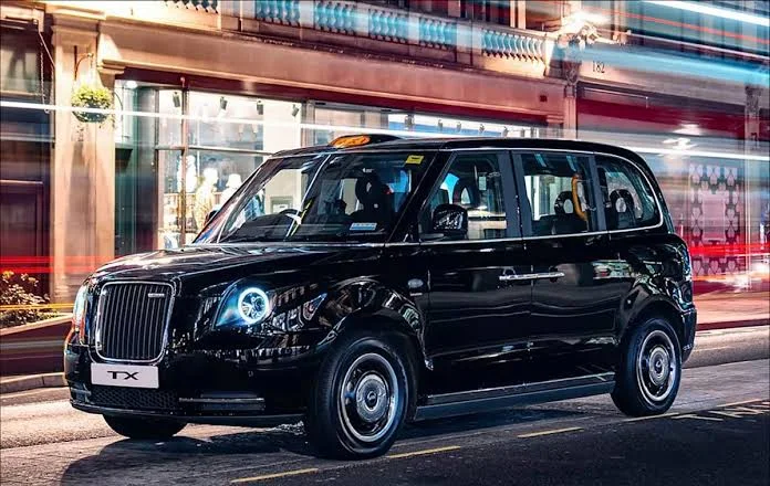 A black London cab on a city street at night